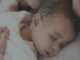 Bebé dormido sobre el pecho de un adulto que lo abraza