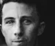 Retrato en blanco y negro del rostro de un hombre joven con pecas que mira fijamente a la cámara