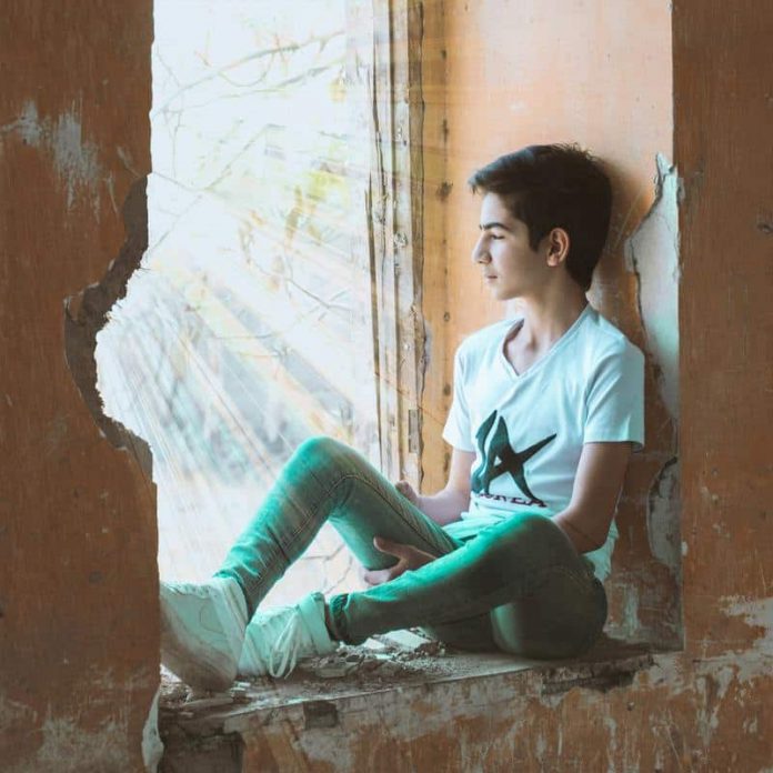 boy-sitting-near-wall-940585