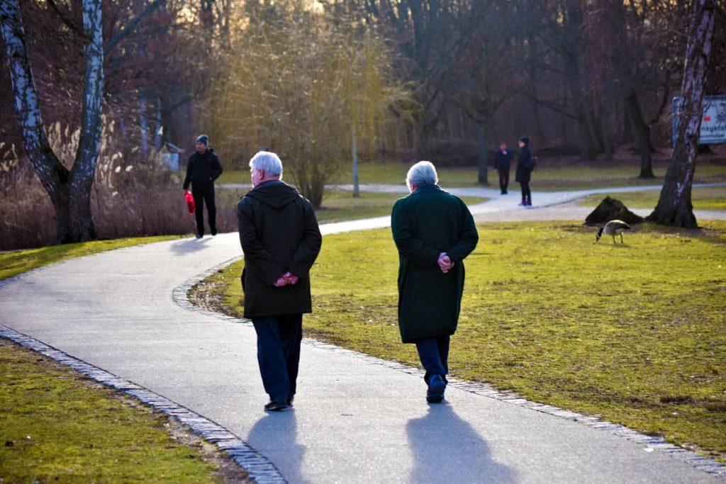 Pareja de personas mayores caminando por un sendero de un parque