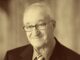 Retrato de Albert Bandura sonriente, en tono sepia
