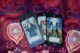 Cartas de tarot ilustradas apoyadas sobre un mantel de estampado rojo y morado