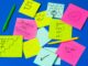 Notas adhesivas de colores con mensajes de ánimo como «Progress not perfection» y «You can do it!»