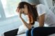 Mujer sentada en un sofá con la cabeza apoyada en la mano y expresión de agotamiento
