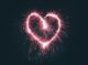 Corazón dibujado con la luz de una bengala sobre un fondo oscuro