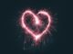 Corazón dibujado con la luz de una bengala sobre un fondo oscuro