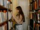 Mujer joven buscando un libro en las estanterías llenas de una biblioteca antigua
