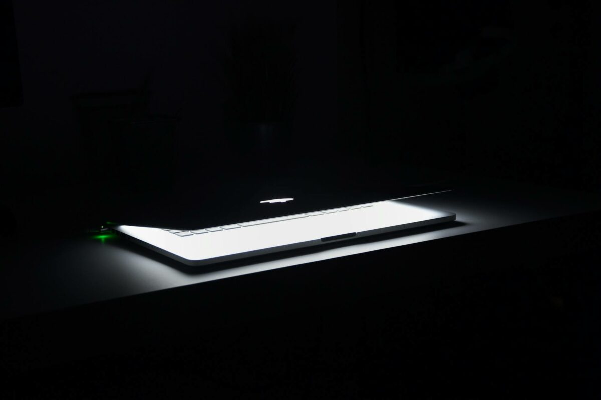 photography of macbook half opened on white wooden surface