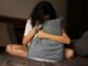 Mujer sentada en la cama abraza con fuerza una almohada y esconde la cara en ella