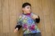 Niño pequeño con camiseta de colores tumbado en el suelo de madera mirando hacia un lado