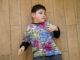 Niño pequeño con camiseta de colores tumbado en el suelo de madera mirando hacia un lado