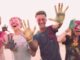 Grupo de jóvenes sonrientes con las caras y las manos manchadas de polvo de colores
