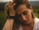 Mujer con la mano en la cabeza y la mirada baja, con expresión de cansancio y tristeza