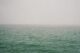 Mar en calma bajo una niebla densa que borra el horizonte