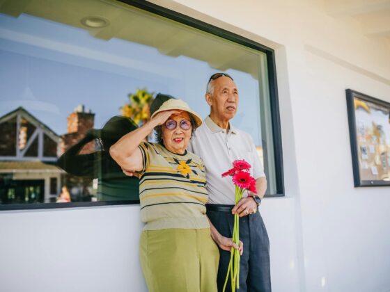 elderly couple standing beside a glass window
