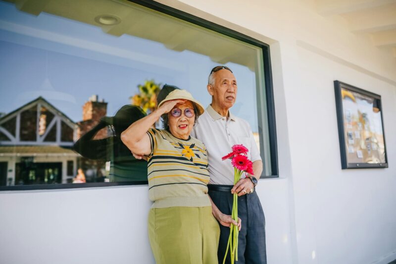 elderly couple standing beside a glass window