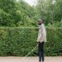 man in beige jacket waling with a white cane