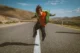 Niño pequeño saltando en medio de una carretera, en un paisaje árido y soleado