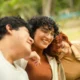 Tres jóvenes adultos sonríen juntos al aire libre